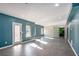 An open concept living room is displayed, with blue accent walls, grey tile flooring, and large windows to allow for natural light at 157 Donovan Ave, Locust Grove, GA 30248