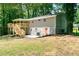 View of the back of the house with a covered deck and orange door, surrounded by greenery and mature trees at 6965 Kimberland Gardens Ln, Lithonia, GA 30058