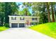 Charming split-level home with a two-car garage, a lush green lawn, and mature trees providing shade at 6965 Kimberland Gardens Ln, Lithonia, GA 30058