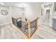 Bright upper hallway featuring laminate flooring, a modern chandelier, and stylish wood and iron railing at 6965 Kimberland Gardens Ln, Lithonia, GA 30058