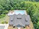 Aerial view highlighting a community pool area with lounge chairs, umbrellas and a clubhouse with lush, mature trees at 1936 Lakeshore Overlook Circle Nw Cir, Kennesaw, GA 30152
