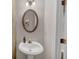 Elegant powder room with a pedestal sink, oval mirror, and stylish lighting fixture at 1936 Lakeshore Overlook Circle Nw Cir, Kennesaw, GA 30152