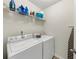 Functional laundry room equipped with modern washer and dryer set, and shelving above for supplies at 1936 Lakeshore Overlook Circle Nw Cir, Kennesaw, GA 30152