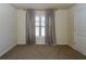 Comfortable bedroom with neutral carpet, light walls, a window with curtains, and a classic white door at 7790 Stratford Ln, Atlanta, GA 30350