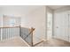 Upstairs hallway featuring carpet flooring, wood and iron railing and view to bedroom and doorway at 5662 Valley Loop, Fairburn, GA 30213