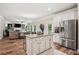 Spacious open kitchen with granite island, stainless steel appliances, and wood floors; view to Gathering room at 5662 Valley Loop, Fairburn, GA 30213