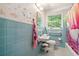 Retro blue-tiled bathroom with vintage fixtures, a window, and colorful accents, offering a unique and nostalgic charm at 6126 Knights Ln, Douglasville, GA 30135