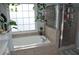 Bathroom featuring a soaking tub with tile surround, glass enclosed shower, and leafy plants at 1951 Barrett Knoll Nw Cir, Kennesaw, GA 30152