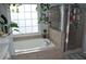 Bathroom with a soaking tub, glass shower, and a large window with plants at 1951 Barrett Knoll Nw Cir, Kennesaw, GA 30152