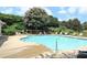 Community pool surrounded by lounge chairs, a fence, a lifeguard stand, and lush trees, perfect for relaxation at 1951 Barrett Knoll Nw Cir, Kennesaw, GA 30152