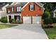 Traditional brick home featuring a two-car garage, covered porch, and well-maintained lawn at 1951 Barrett Knoll Nw Cir, Kennesaw, GA 30152