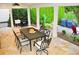 Covered outdoor patio with stone flooring features dining table, outdoor kitchen area, and lush landscaping at 1951 Barrett Knoll Nw Cir, Kennesaw, GA 30152