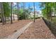 Backyard with mature trees, an iron fence, and a brick walkway leading to the beautiful home at 6440 Westchester Pl, Cumming, GA 30040