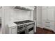 Gourmet kitchen featuring professional-grade range, marble backsplash, and white cabinetry offering both style and functionality at 6440 Westchester Pl, Cumming, GA 30040