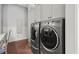 Modern laundry room showcasing front loading washer and dryer set with brick flooring and ample cabinet space at 6440 Westchester Pl, Cumming, GA 30040