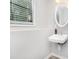Bright powder room with an oval mirror and a wall-mounted sink at 8605 Stone Creek Ct, Douglasville, GA 30135