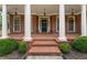 Charming front porch with brick flooring, white columns, and lush landscaping at 412 Mill Stream Way, Woodstock, GA 30188