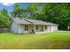 A single-story home with gray siding, a charming front porch, and a lush green lawn at 130 Sunnybrook Ln, Woodstock, GA 30188