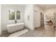 Bright bathroom with soaking tub and view into walk-in closet and the main bedroom beyond at 3233 Osborne Ne Rd, Brookhaven, GA 30319