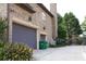 Attached two-car garage and brick exterior detailing, accompanied by lush landscaping at 4663 Mossey Dr, Lithonia, GA 30038