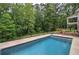 In-ground pool surrounded by a concrete patio, steps, landscaping, and a fenced backyard at 6095 Fords Nw Rd, Acworth, GA 30101