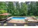 A gorgeous pool with lounge chairs surrounded by a beautiful wooded landscape and black aluminum fencing at 6095 Fords Nw Rd, Acworth, GA 30101
