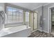 Bright bathroom with a soaking tub, glass enclosed shower, a large window, and wood look floors at 859 Scales Rd, Suwanee, GA 30024