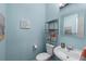 Cozy powder room featuring blue walls, white toilet and sink, and decoratively placed artwork at 859 Scales Rd, Suwanee, GA 30024