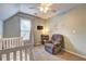 Bedroom featuring white crib, gray recliner and ceiling fan at 2230 Laurel Lake Dr, Suwanee, GA 30024