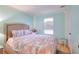 Bright bedroom featuring light blue walls, hardwood floors, a large window and a cozy bed with patterned bedding at 2573 Mistletoe Ln, Snellville, GA 30039