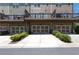 Townhome garages with a paved driveway and manicured landscaping in a well-maintained community at 209 Snapdragon St, Woodstock, GA 30188