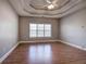 Bedroom with wood floors, ceiling fan, tray ceiling, and a large window at 2500 Rosehill Cir, Lithia Springs, GA 30122