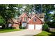 Well-maintained two-story brick home with a two-car garage and a lush green lawn, surrounded by mature trees at 2720 Stillwater Lake Ln, Marietta, GA 30066