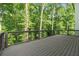 A large wooden deck with black metal railings provides scenic views of the surrounding lush greenery at 7650 Abbey Glen Dr, Cumming, GA 30028