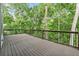 Expansive wooden deck with black metal railings surrounded by lush greenery, creating a serene outdoor retreat at 7650 Abbey Glen Dr, Cumming, GA 30028