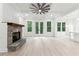Open living room with a stone fireplace, hardwood floors, coffered ceilings, and glass doors to the outdoors at 7650 Abbey Glen Dr, Cumming, GA 30028