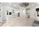 A spacious open-plan living room with hardwood floors, kitchen, modern lighting, and coffered ceilings at 7650 Abbey Glen Dr, Cumming, GA 30028