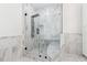 Spa-like walk-in shower with marble tiles, a built-in seat, and modern shower fixtures at 7650 Abbey Glen Dr, Cumming, GA 30028