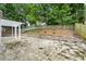 Stone patio with white pergola, retaining wall, and grassy backyard at 3040 Ivey Oaks Ln, Roswell, GA 30076