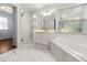 Bathroom featuring a glass shower, tub, white cabinets, and marble floors at 3040 Ivey Oaks Ln, Roswell, GA 30076