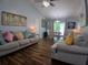Bright living room featuring wood floors, gray couches, and sliding doors to the backyard at 3356 Hollow Ct, Lawrenceville, GA 30044
