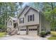 Exterior side view showcasing a two-car garage, stone foundation, and lush greenery at 3365 Ne Ivy Lake Drive Northeast Dr, Buford, GA 30519