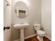 Powder room features pedestal sink, oval mirror, and wood floors at 4404 Village Field Pl, Suwanee, GA 30024