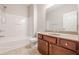 Bathroom with white tub and shower and wooden vanity with granite countertop, offering modern comfort at 4404 Village Field Pl, Suwanee, GA 30024