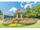 Landscaped community signage with colorful flowers, manicured lawn, and blue sky above the Vilage Grove entrance at 4404 Village Field Pl, Suwanee, GA 30024