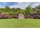 Lush backyard showcasing a practical storage shed amidst a well-maintained lawn and garden at 206 Traditions Dr, Loganville, GA 30052