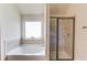 Modern bathroom featuring a soaking tub, a large window and a glass-enclosed shower stall at 206 Traditions Dr, Loganville, GA 30052