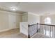 Upstairs hallway with neutral carpet and paint, decorative molding, and view of an arched window and chandelier at 206 Traditions Dr, Loganville, GA 30052