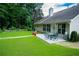 Back patio with an outdoor dining set and lush green lawn, ideal for enjoying meals outside at 2407 Cove Lake Way, Lithonia, GA 30058