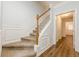 Elegant staircase featuring wood railing, neutral carpeting and beautiful white wall paneling at 5589 Trace Views Dr, Norcross, GA 30071